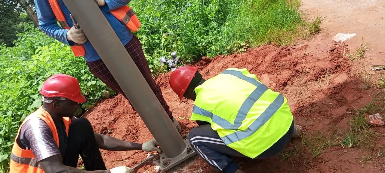 Techniciens fixant la base d'un mât de lampadaire solaire